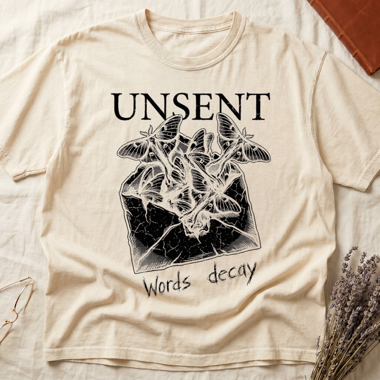 Ivory tee with 'UNSENT' in serif type, 'Words decay' brush text, luna moths from torn envelope in crosshatched ink