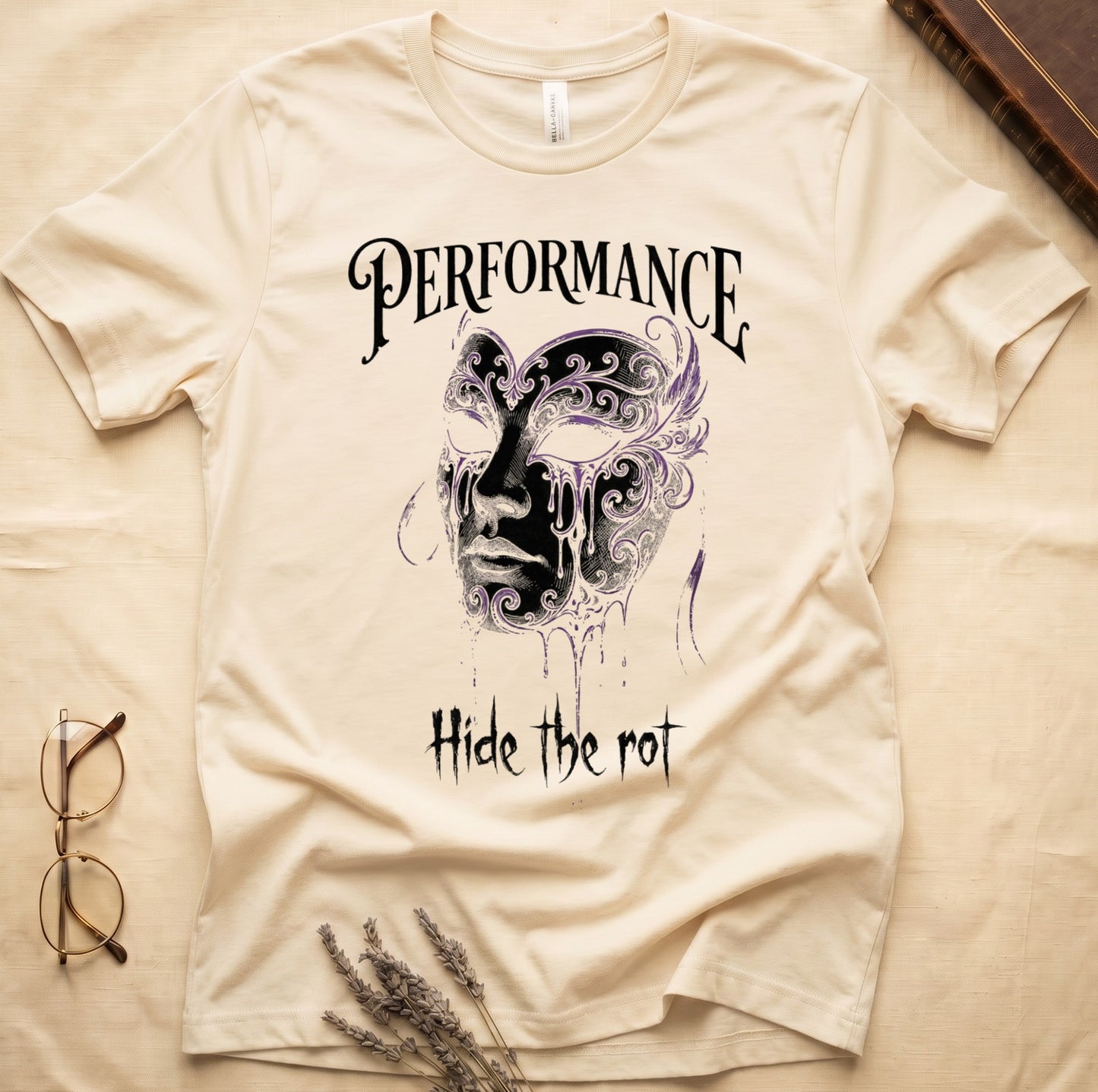 Natural tee with ornate Venetian mask in cream and purple filigree dripping ink, "PERFORMANCE" top, "Hide the rot" below.