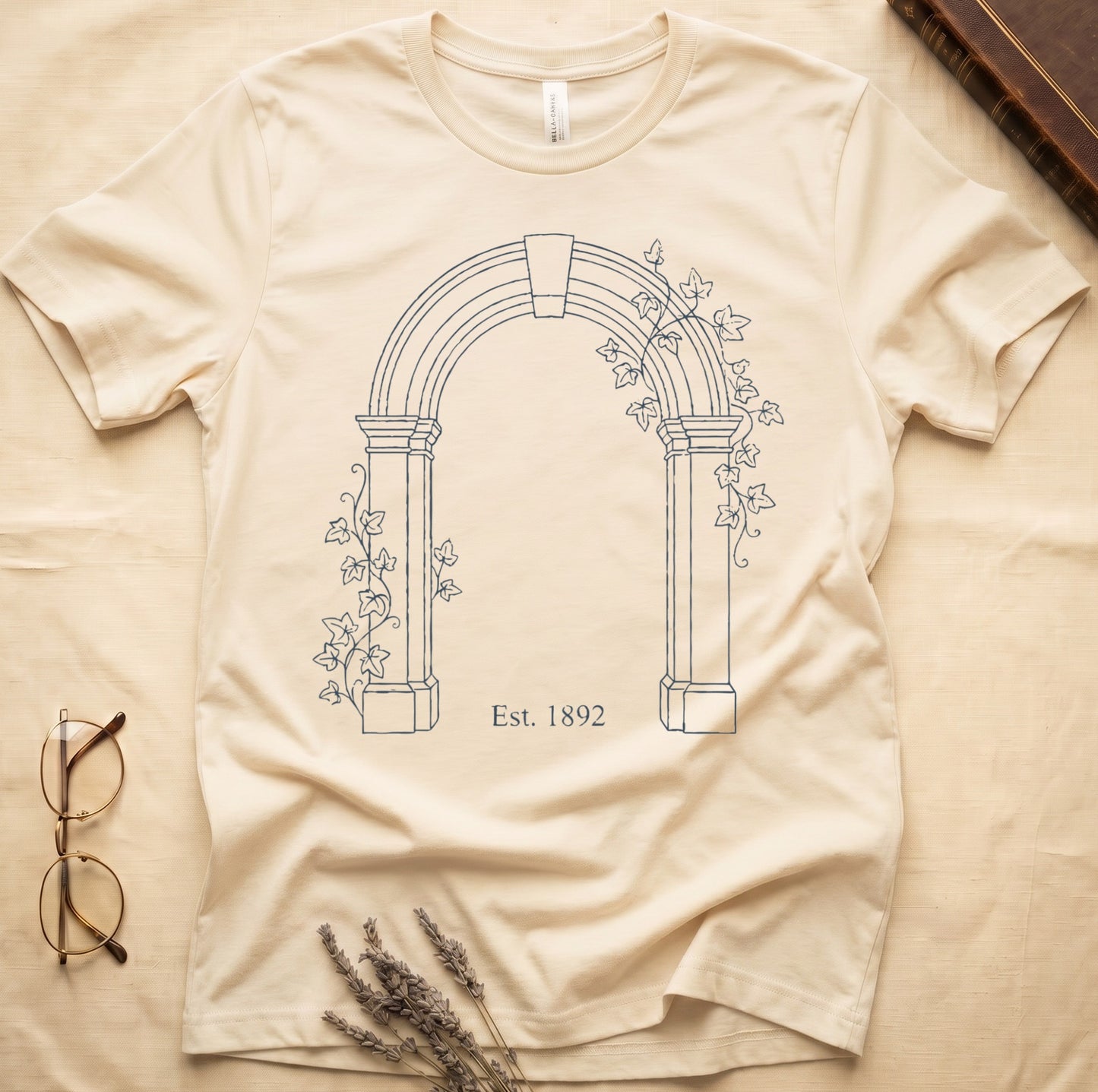 Natural tee with Gothic stone archway in cream linework, ivy climbing the columns, "Est. 1892" inscribed at the base.