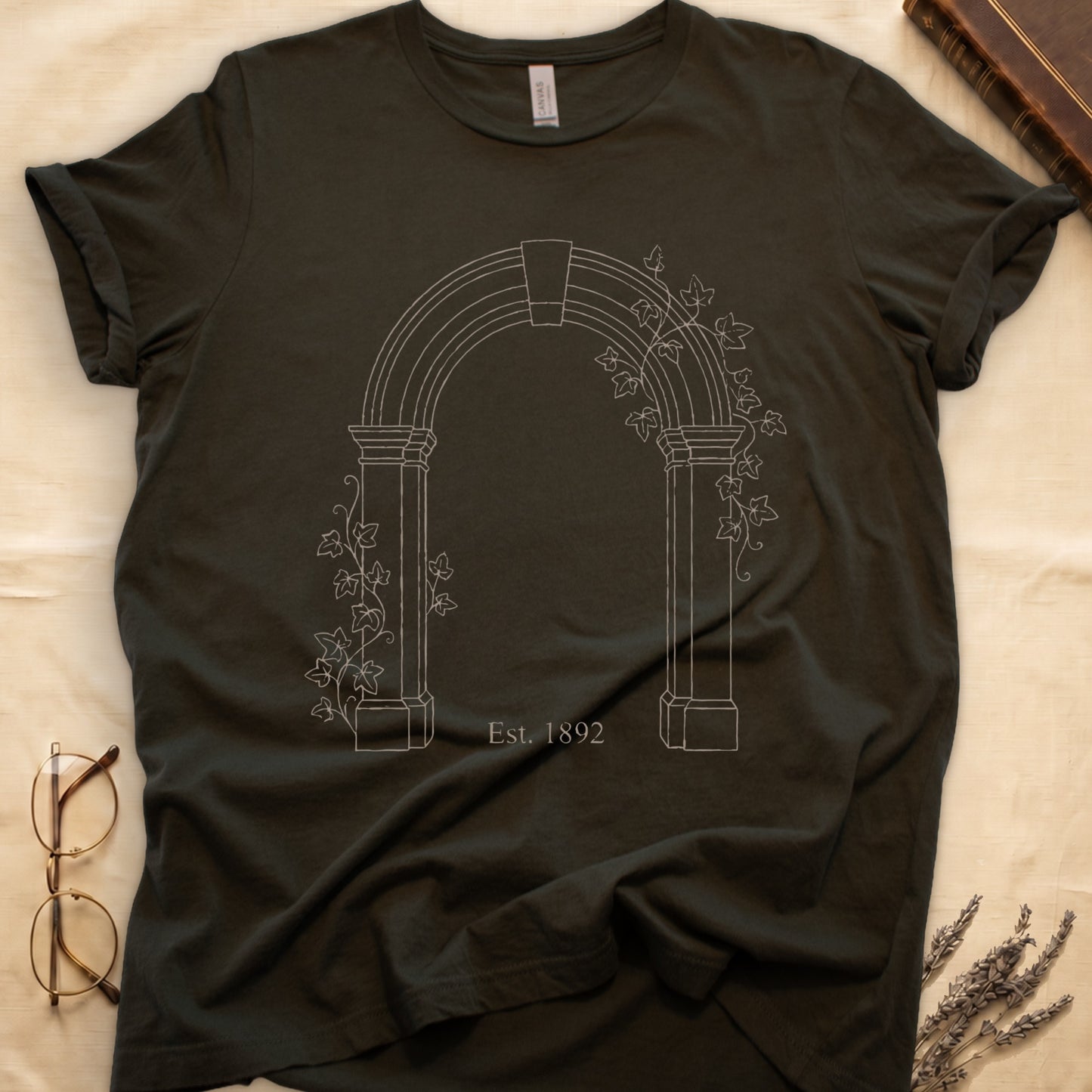 Military Green tee with Gothic stone archway in cream linework, ivy climbing the columns, "Est. 1892" inscribed at the base.