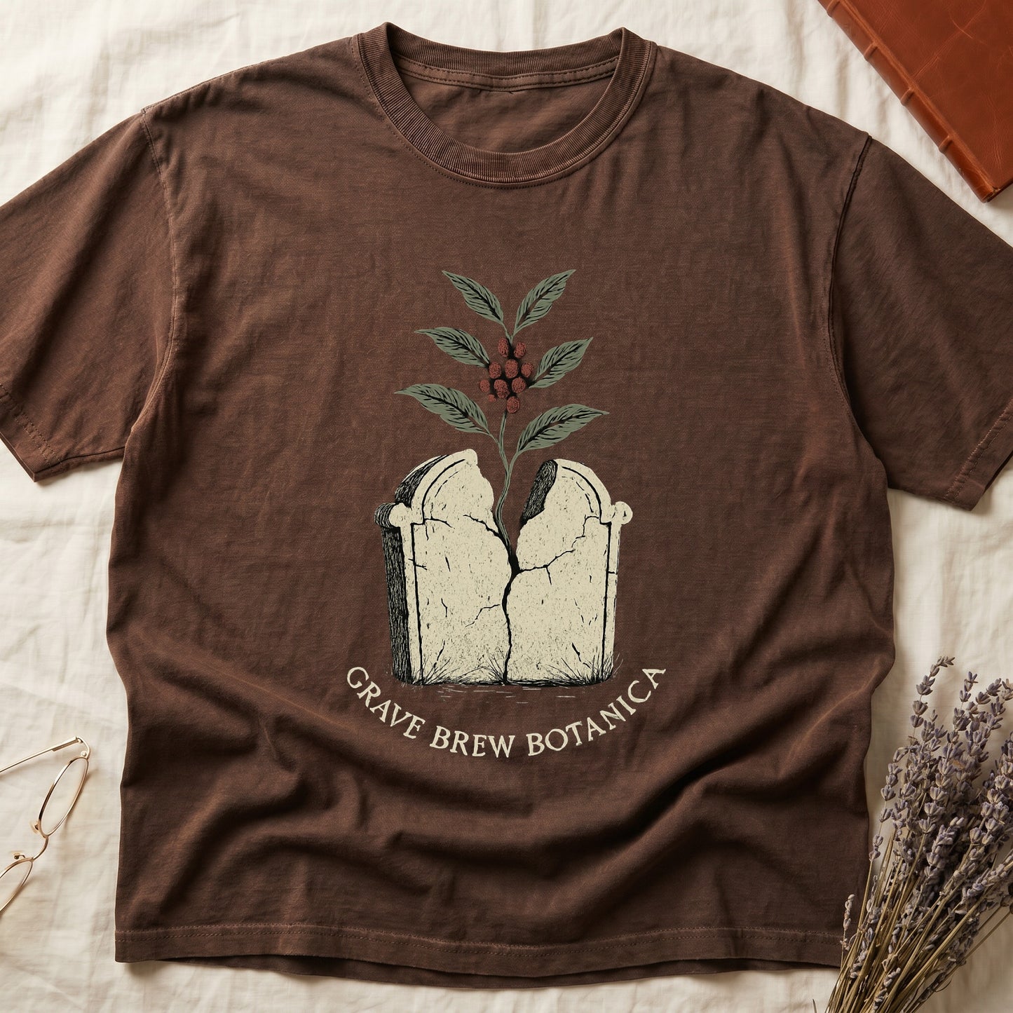 Brown t-shirt with cracked tombstone and coffee plant graphic, text reads "Grave Brew Botanica".
