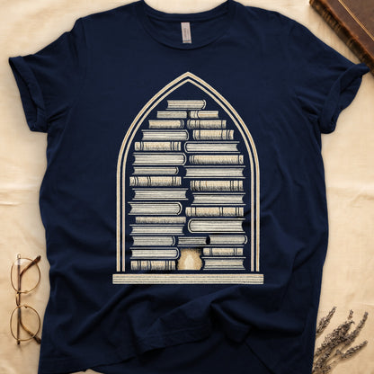 Navy tee with gothic arch frame, columns of leather-bound books inside, sunburst medallion at base, cream engraved linework.