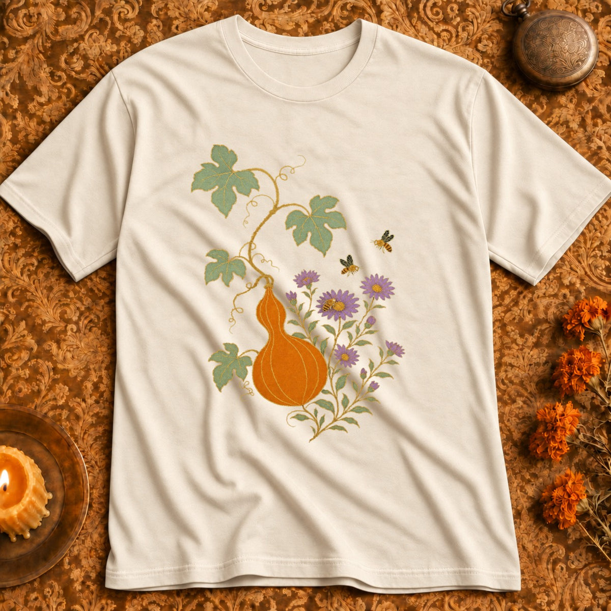 Cream t-shirt with an orange gourd, purple flowers, and bees design.
