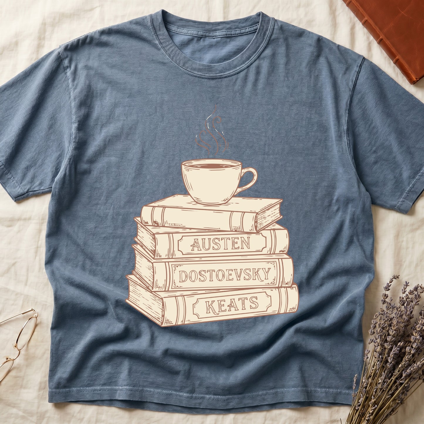 Blue Jean tee with stack of vintage books labeled "AUSTEN," "DOSTOEVSKY," "KEATS" topped with a steaming coffee cup.