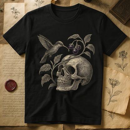 Black tee with sepia engraved skull, nightshade vine and dark-purple berries wrapping around, hummingbird at upper left.