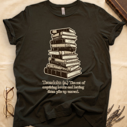 Military Green tee with stack of vintage hardcovers, "Tsundoku (n.) The act of acquiring books and letting them pile up unread."