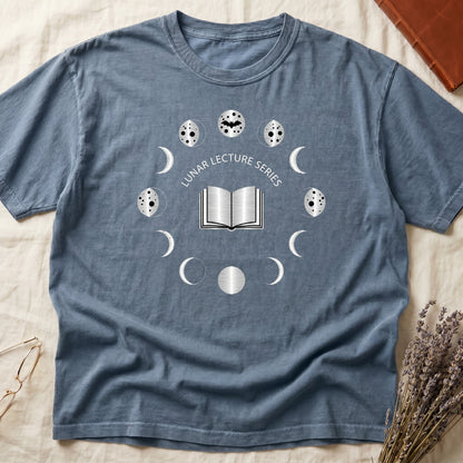 Blue Jean tee with open book at center, ring of cream moon phases around, curved "LUNAR LECTURE SERIES" double-arc above.