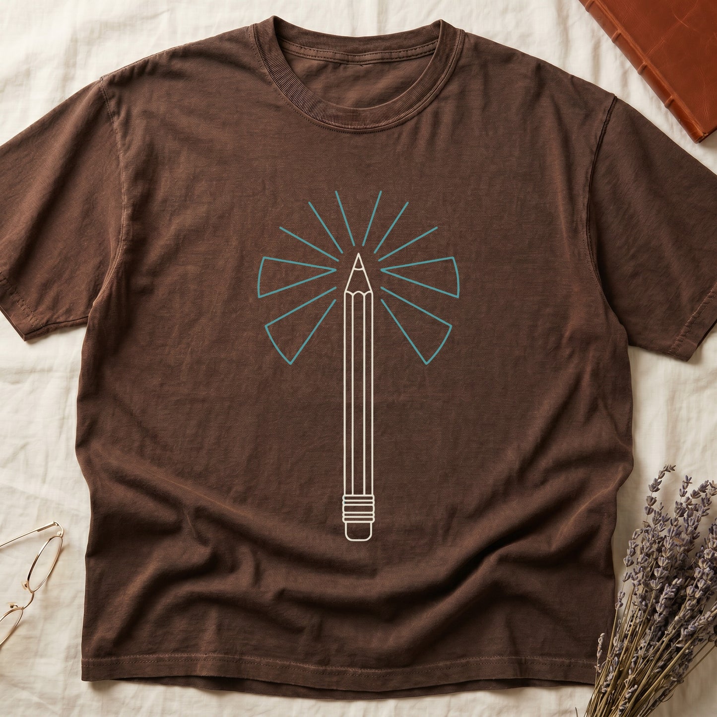 Espresso tee with single vertical graphite pencil in cream linework, fan of teal and grey rays radiating behind.