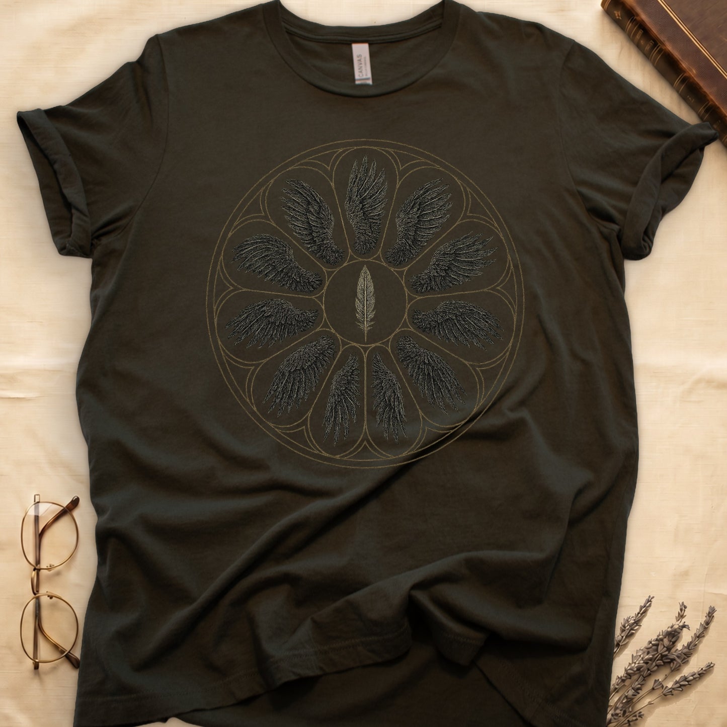 Military Green tee with sepia rose-window of eight feathered wings around central feather, engraved linework on parchment ground.