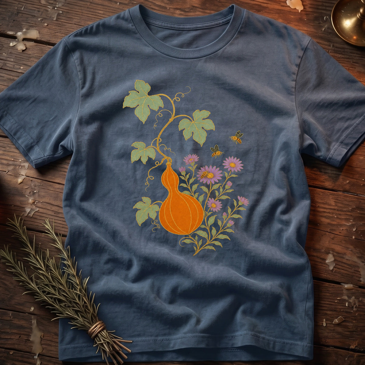 Blue t-shirt with an orange gourd, flowers, and bees graphic design.