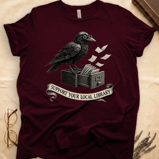 Navy tee with raven writing on "823.4" parchment by candlelight, ink jar beside, "MIDNIGHT CATALOGUER" banner above.