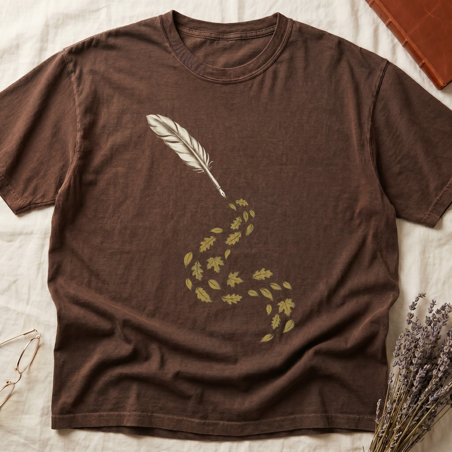 Espresso tee with antique quill pen in cream linework, oak and maple leaves cascading from the nib in gold and green.