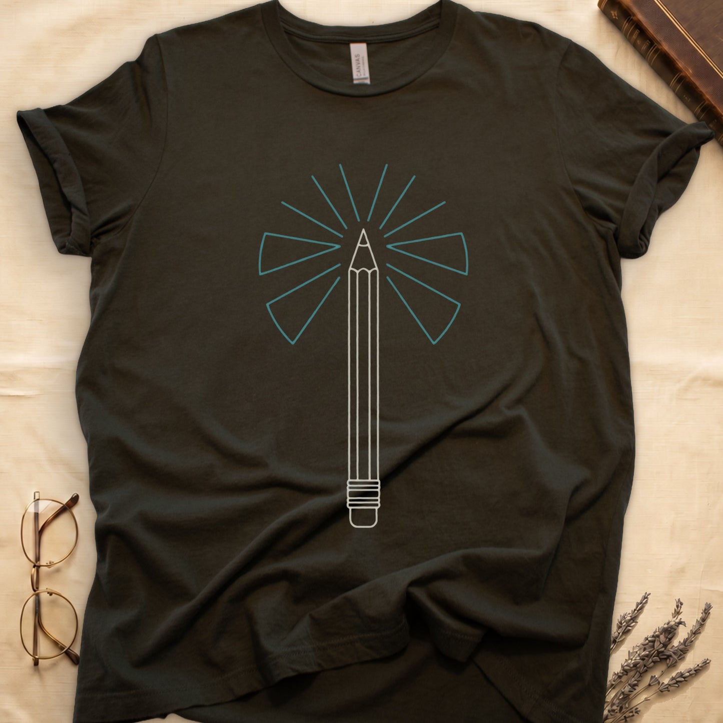 Military Green tee with single vertical graphite pencil in cream linework, fan of teal and grey rays radiating behind.