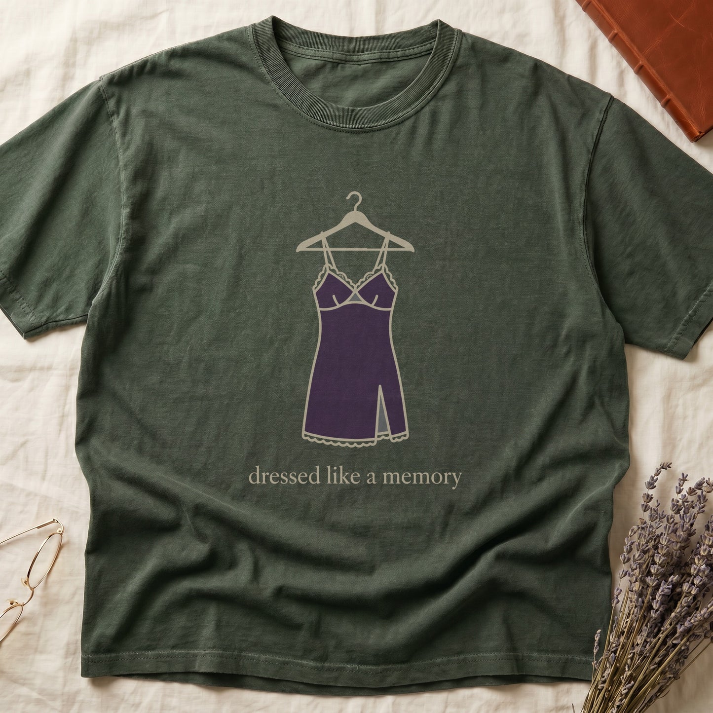 Green tee with dusty plum slip dress on cream hanger and "dressed like a memory" in lowercase cream serif below.