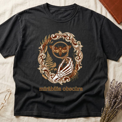Black tee with skeletal hand, magnifying glass, death's-head moth, ferns on green, "mīrābilia obscūra" in Latin italic.
