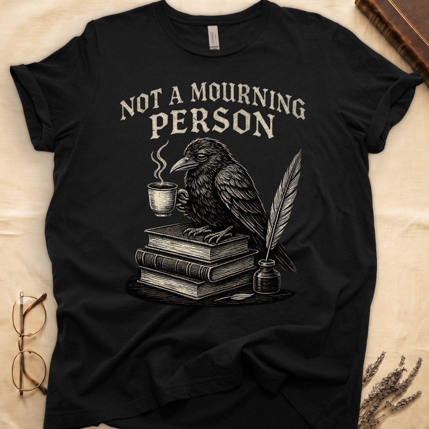 Military Green tee with raven holding coffee on stack of books, quill in inkwell, "NOT A MOURNING PERSON" distressed serif top.
