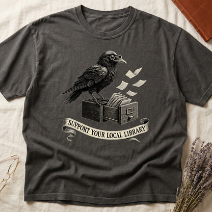 Green tee with raven writing on "823.4" parchment by candlelight, ink jar beside, "MIDNIGHT CATALOGUER" banner above.