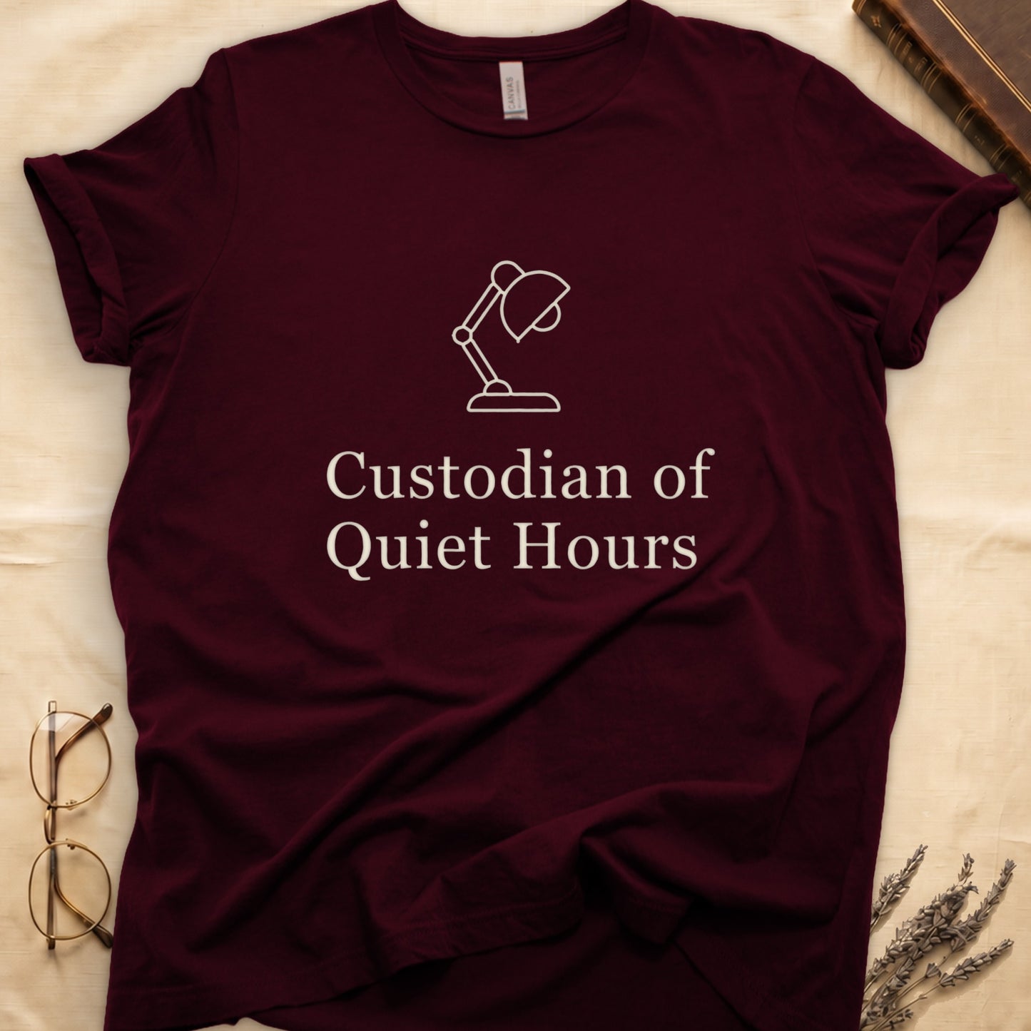 Maroon tee with vintage desk lamp in cream linework above "Custodian of Quiet Hours" in distressed Art Deco caps.