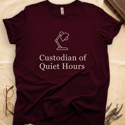 Maroon tee with vintage desk lamp in cream linework above "Custodian of Quiet Hours" in distressed Art Deco caps.