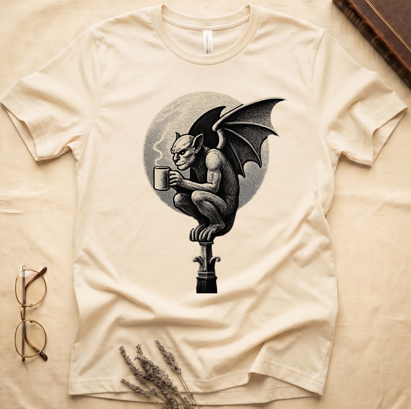 Natural tee with gargoyle on stone pinnacle holding coffee mug, cream-parchment full moon behind, engraving style.