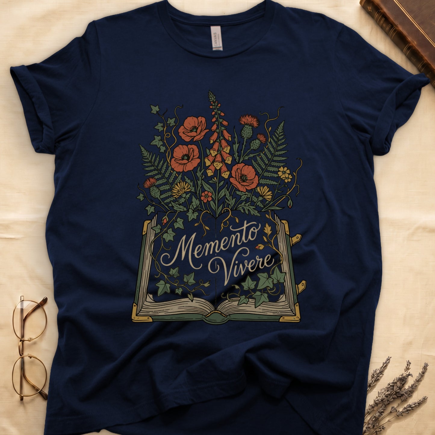Navy tee with open book and botanical illustration, red poppies, golden foxglove, ferns and ivy spilling from the pages.