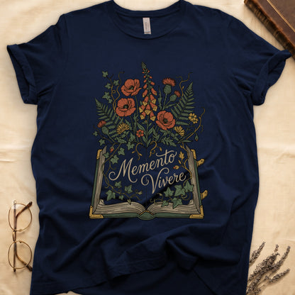 Navy tee with open book and botanical illustration, red poppies, golden foxglove, ferns and ivy spilling from the pages.