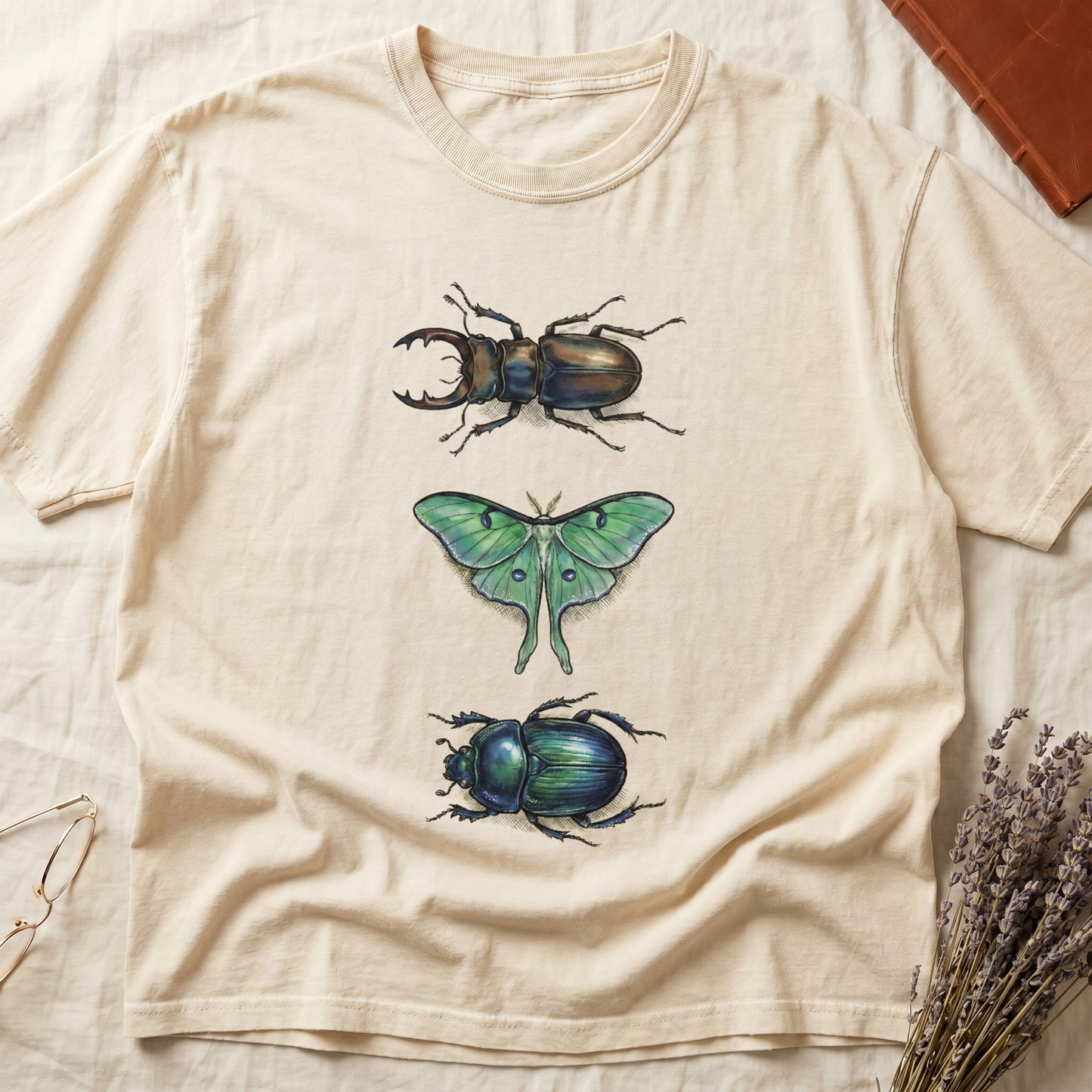 Black tee with three-panel Ivory-history plate: stag beetle, luna moth, scarab beetle in ink on yellow ground.
