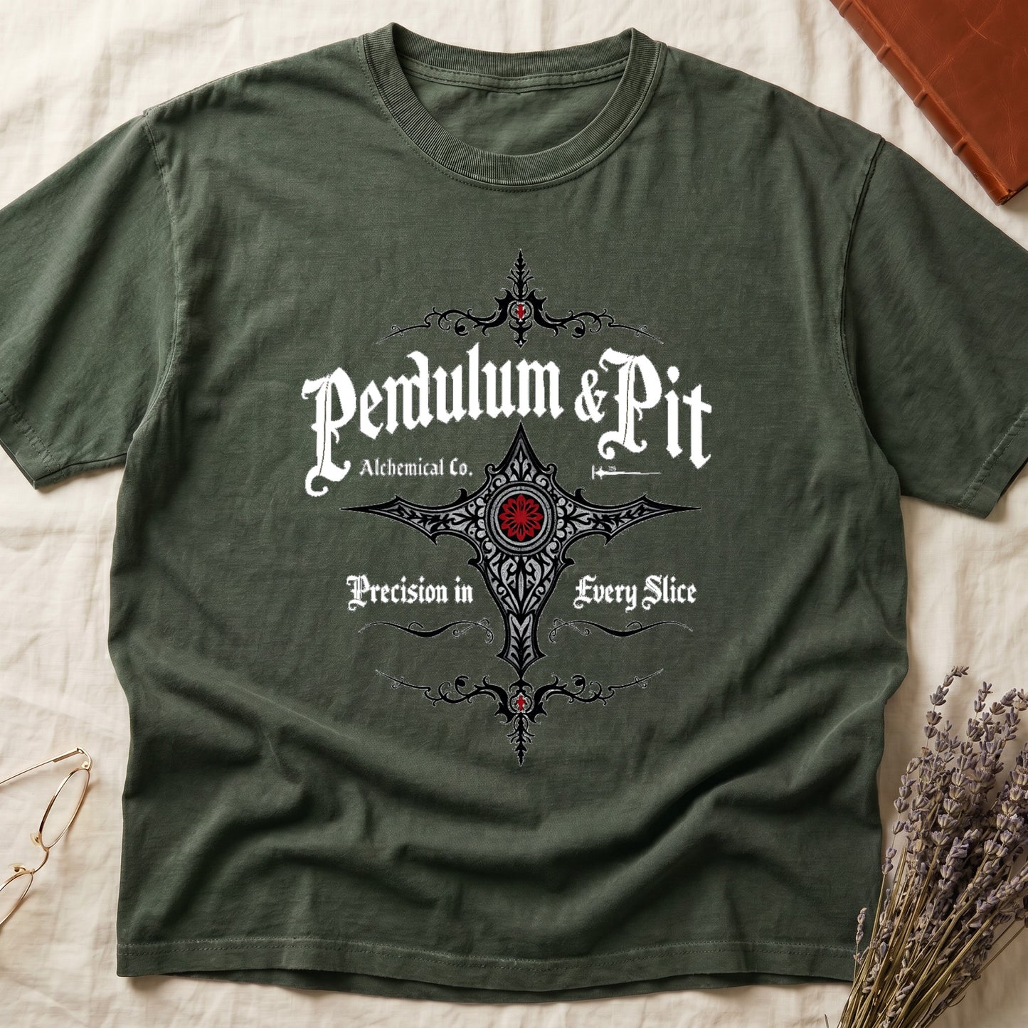 Green tee with white talismanic cross, "Pendulum & Pit Alchemical Co.," "Precision in Every Slice" banner ribbons.