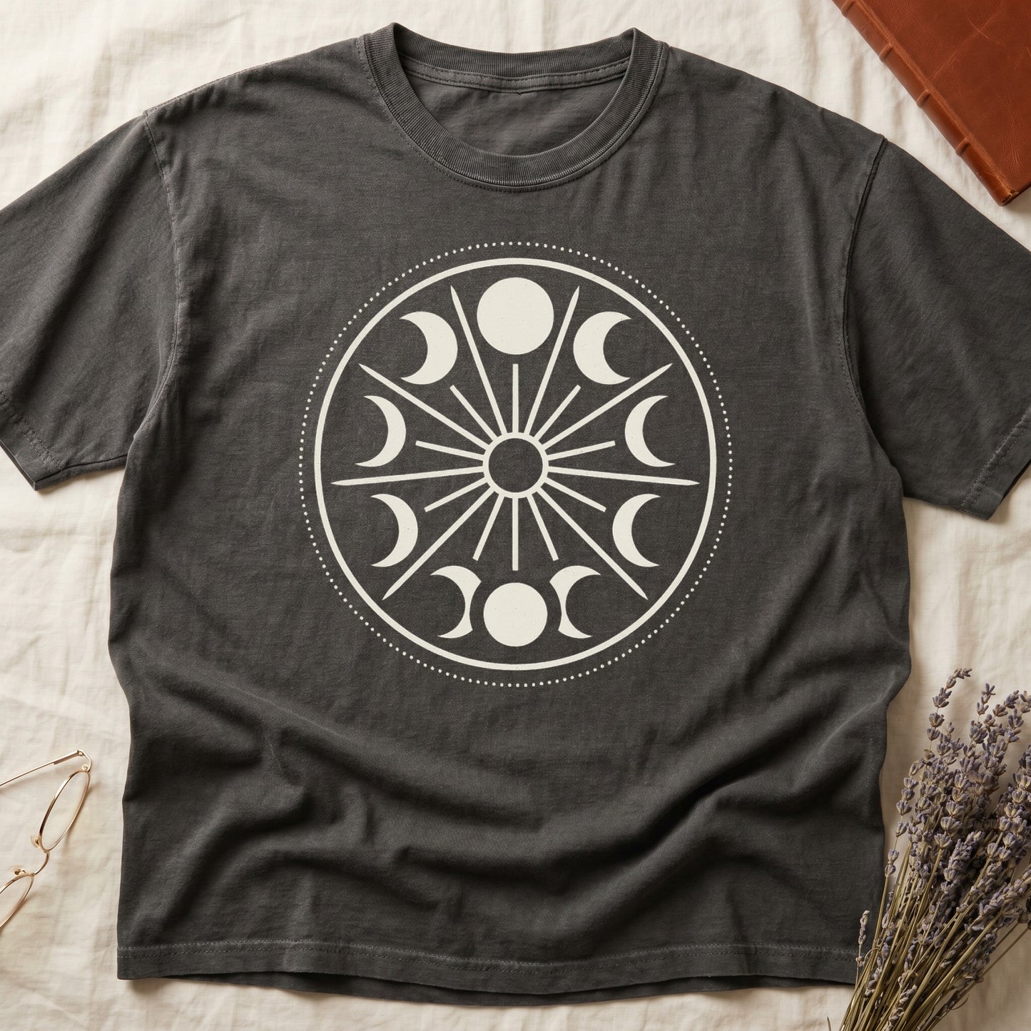 Pepper tee with cream lunar orrery wheel, dotted ring, radial sunburst, moon phases around perimeter, central star.