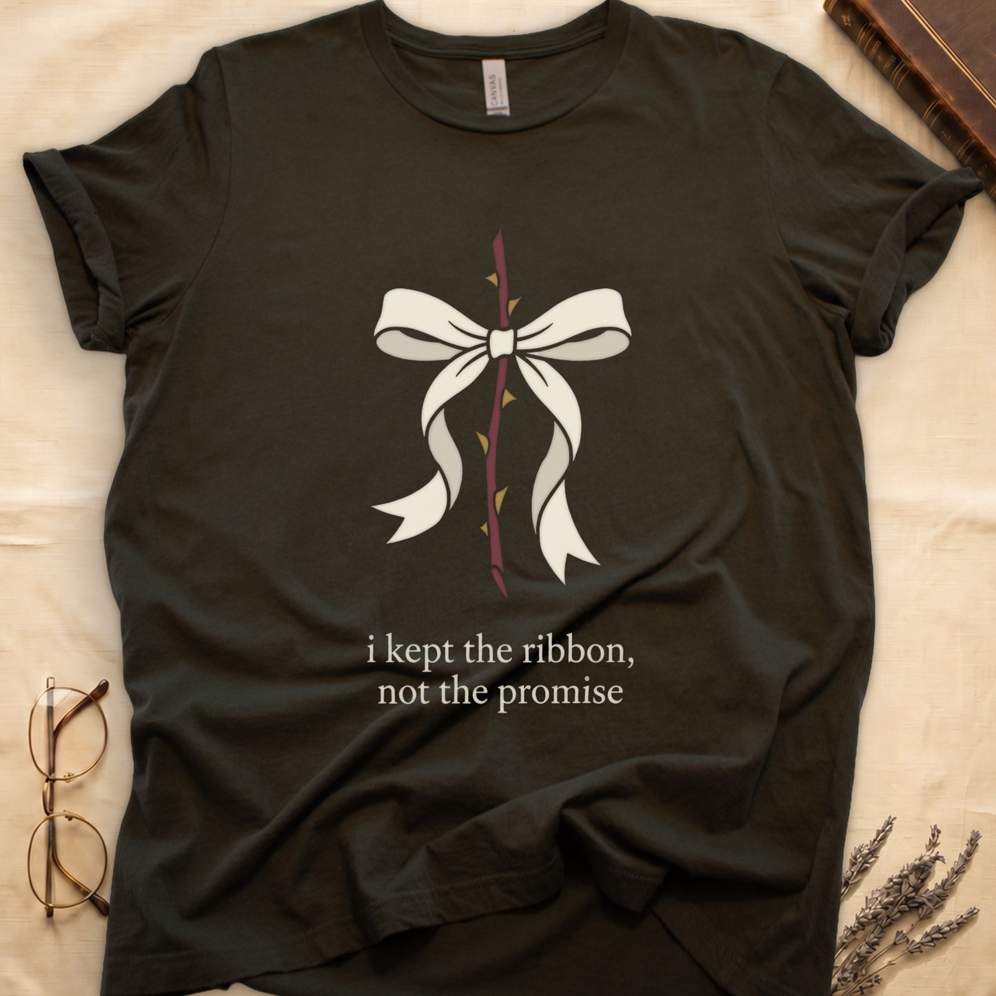 Military Green tee with cream bow tied around thorny rose stem, "i kept the ribbon, not the promise" in cream serif below.