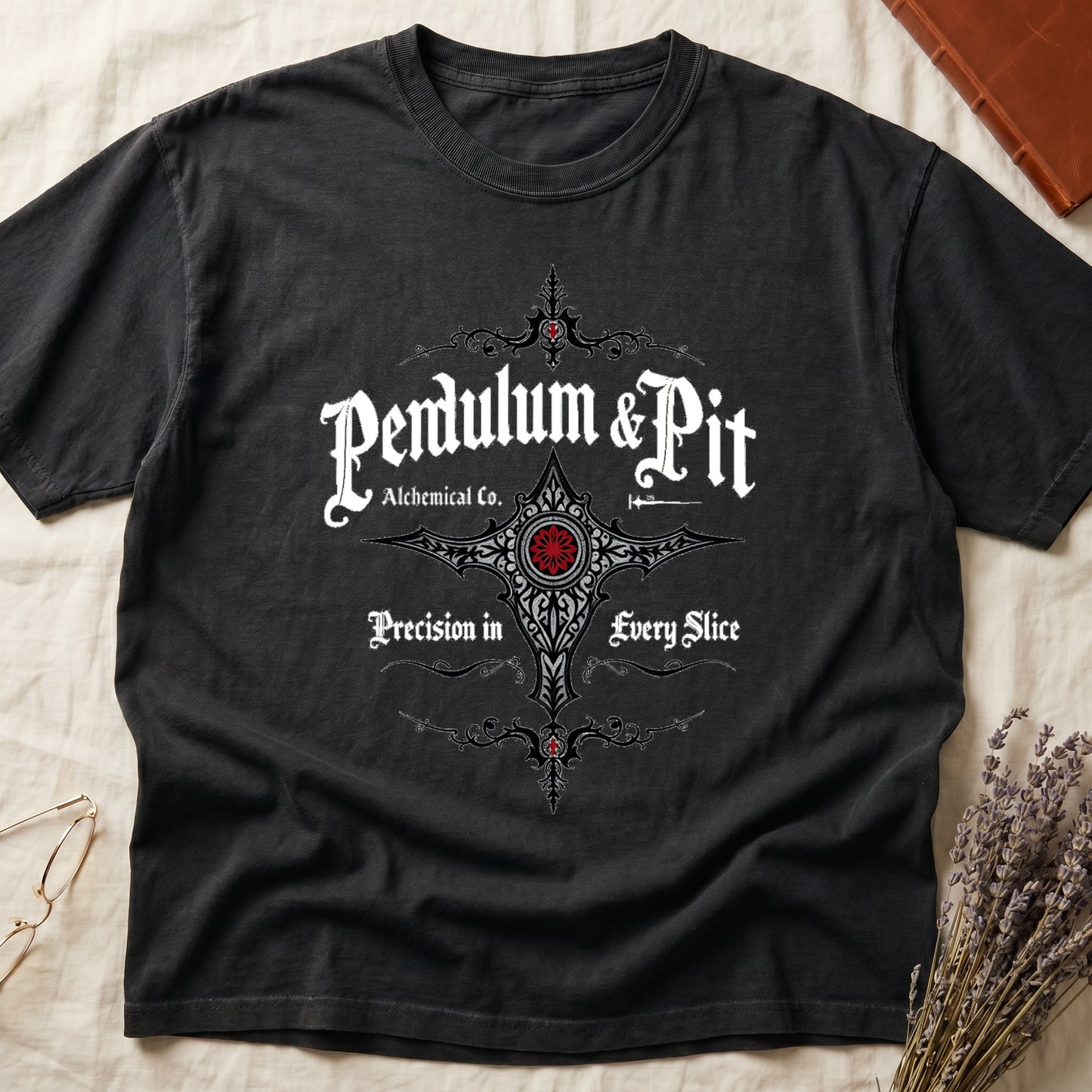 Black tee with white talismanic cross, "Pendulum & Pit Alchemical Co.," "Precision in Every Slice" banner ribbons.