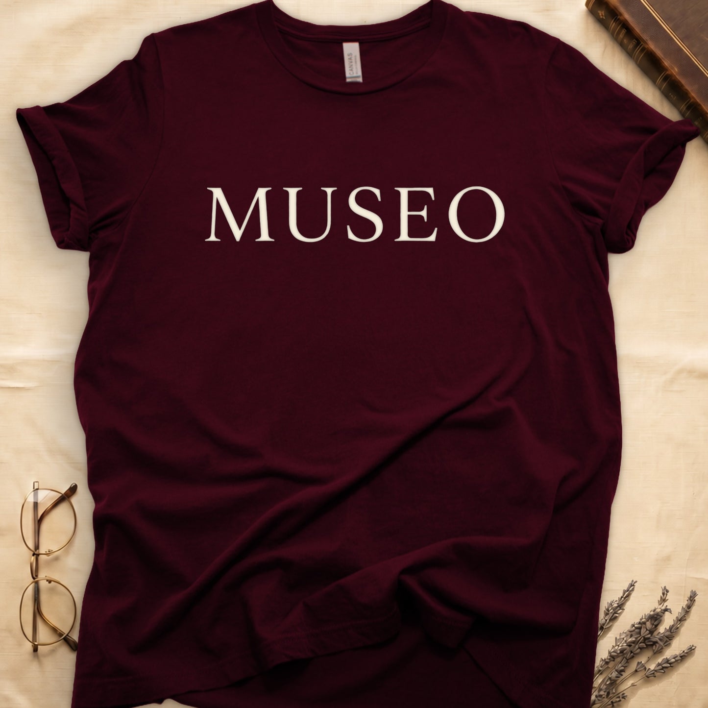 Maroon tee with "MUSEO" in oversized cream serif capitals, minimalist typographic design.