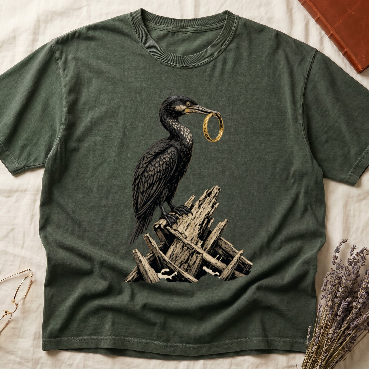 Dark green t-shirt with a cormorant holding a gold ring perched on wood debris.