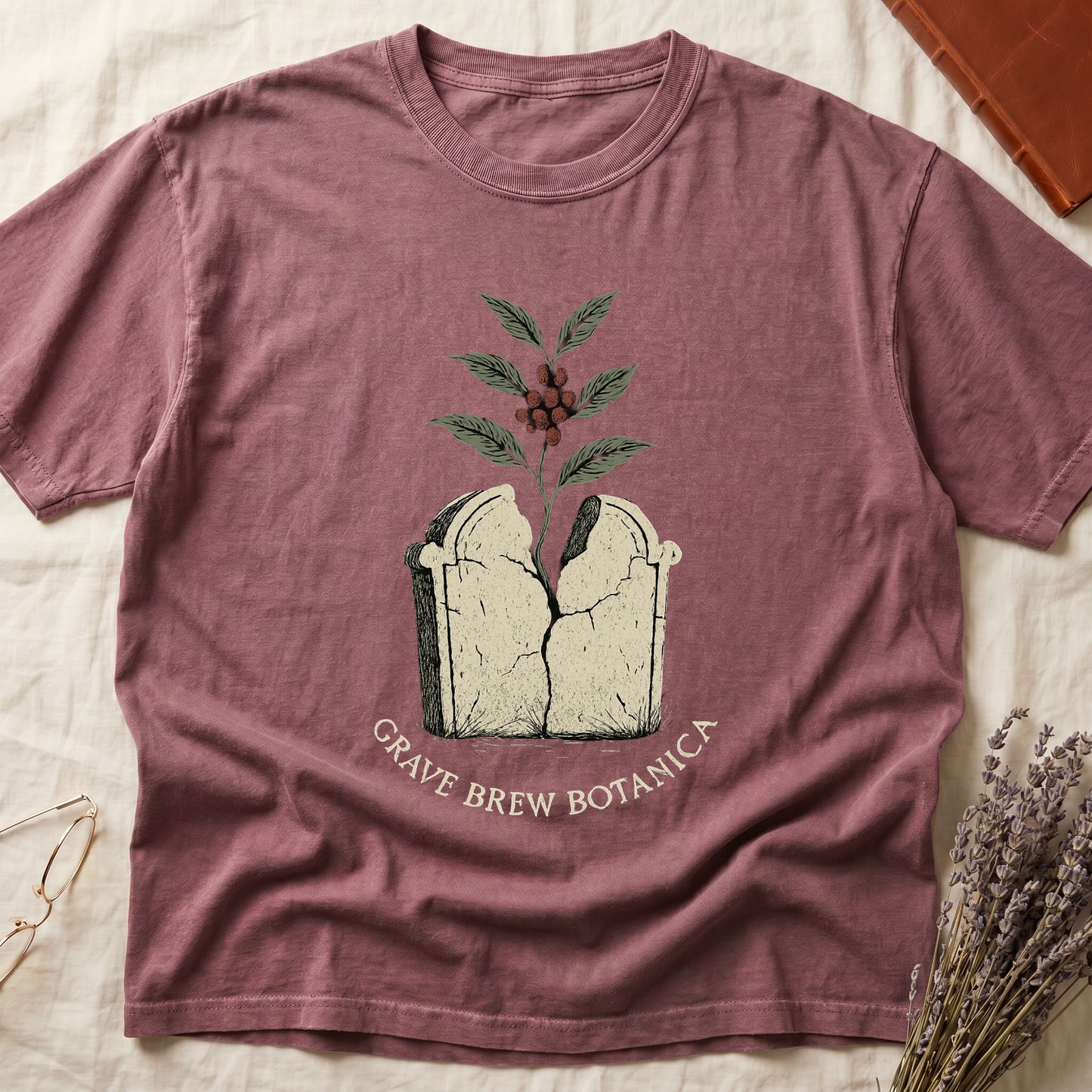 T-shirt with graphic of cracked tombstone with plant growing out, "Grave Brew Botanica" text.