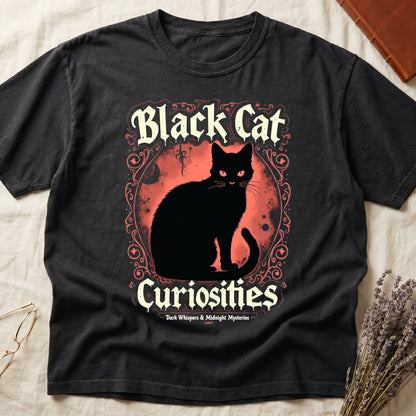 Black tee with black cat, red eyes, red-orange moon, "Black Cat Curiosities," "Dark Whispers & Midnight Mysteries."