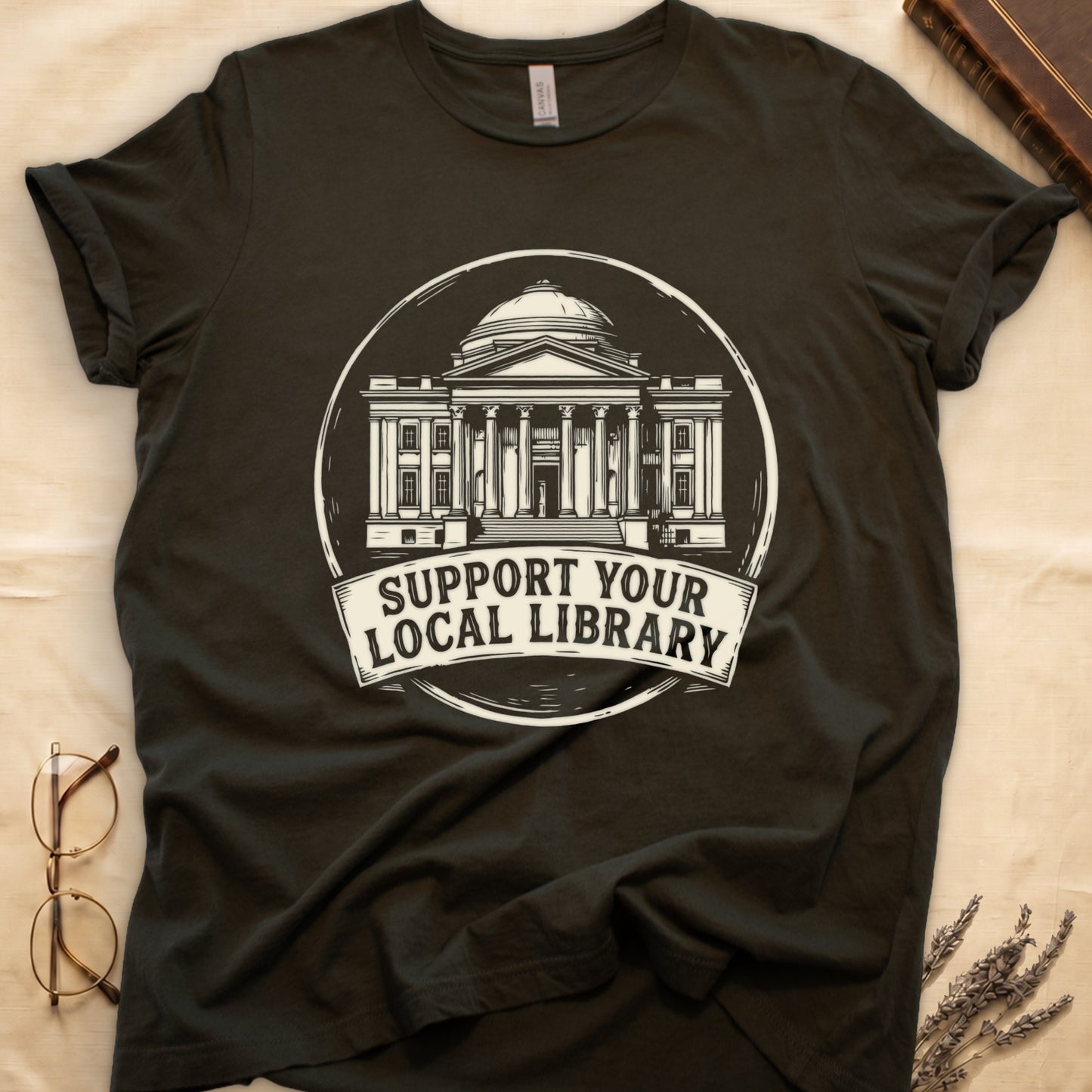 Military Green tee with circular cream badge of a classical library building, "SUPPORT YOUR LOCAL LIBRARY" on a banner below.