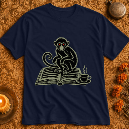 Dark navy t-shirt featuring a monkey with red eyes sitting on an open book next to a coffee cup.