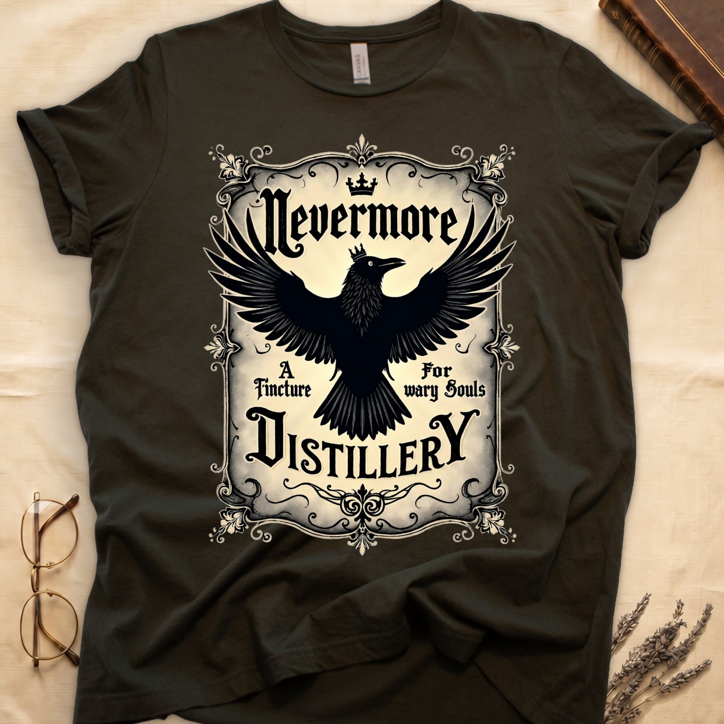Military Green tee with antique label, crowned raven, blackletter "Nevermore" top, "A Tincture For wary Souls," "DISTILLERY" bottom.