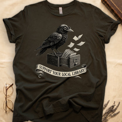 Maroon tee with raven writing on "823.4" parchment by candlelight, ink jar beside, "MIDNIGHT CATALOGUER" banner above.