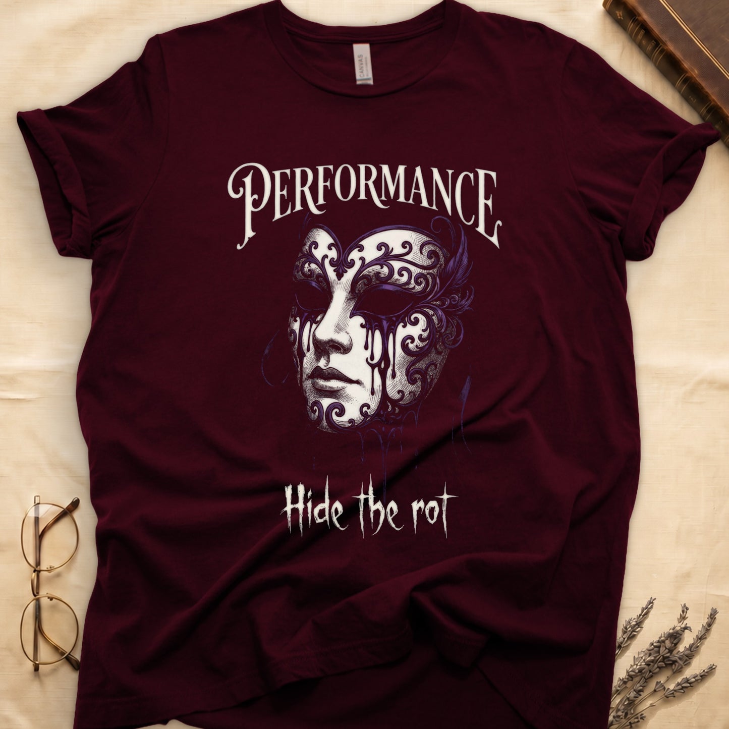Maroon tee with ornate Venetian mask in cream and purple filigree dripping ink, "PERFORMANCE" top, "Hide the rot" below.