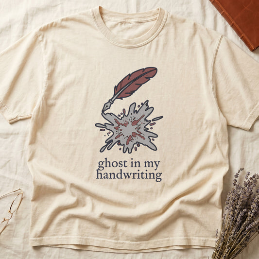 Ivory tee with burgundy quill pen and grey ink splatter, "ghost in my handwriting" cream serif below.