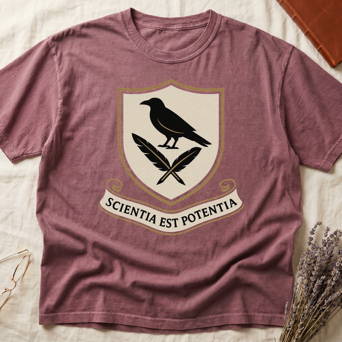 Dark Rose tee with cream-and-gold heraldic shield, black raven over crossed quills, scroll banner "SCIENTIA EST POTENTIA" below.