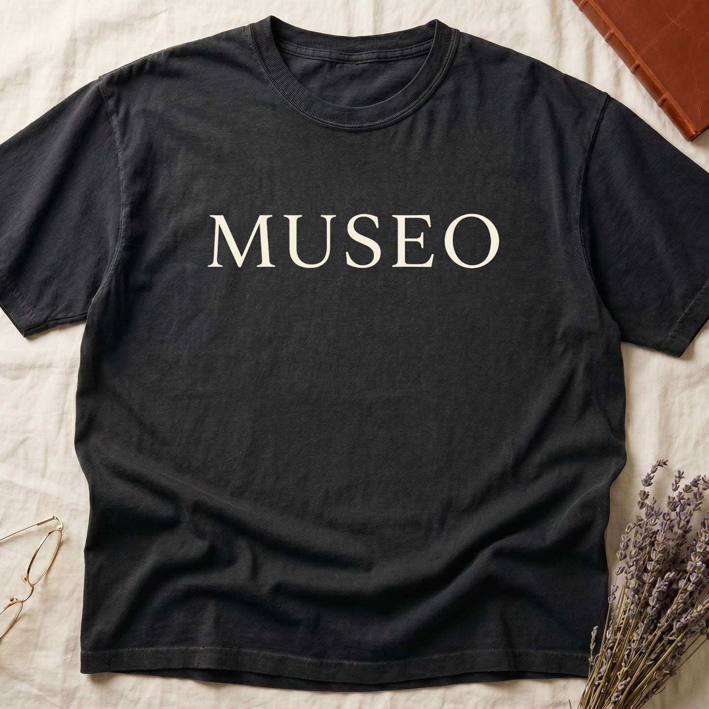 Black tee with "MUSEO" in oversized cream serif capitals, minimalist typographic design.