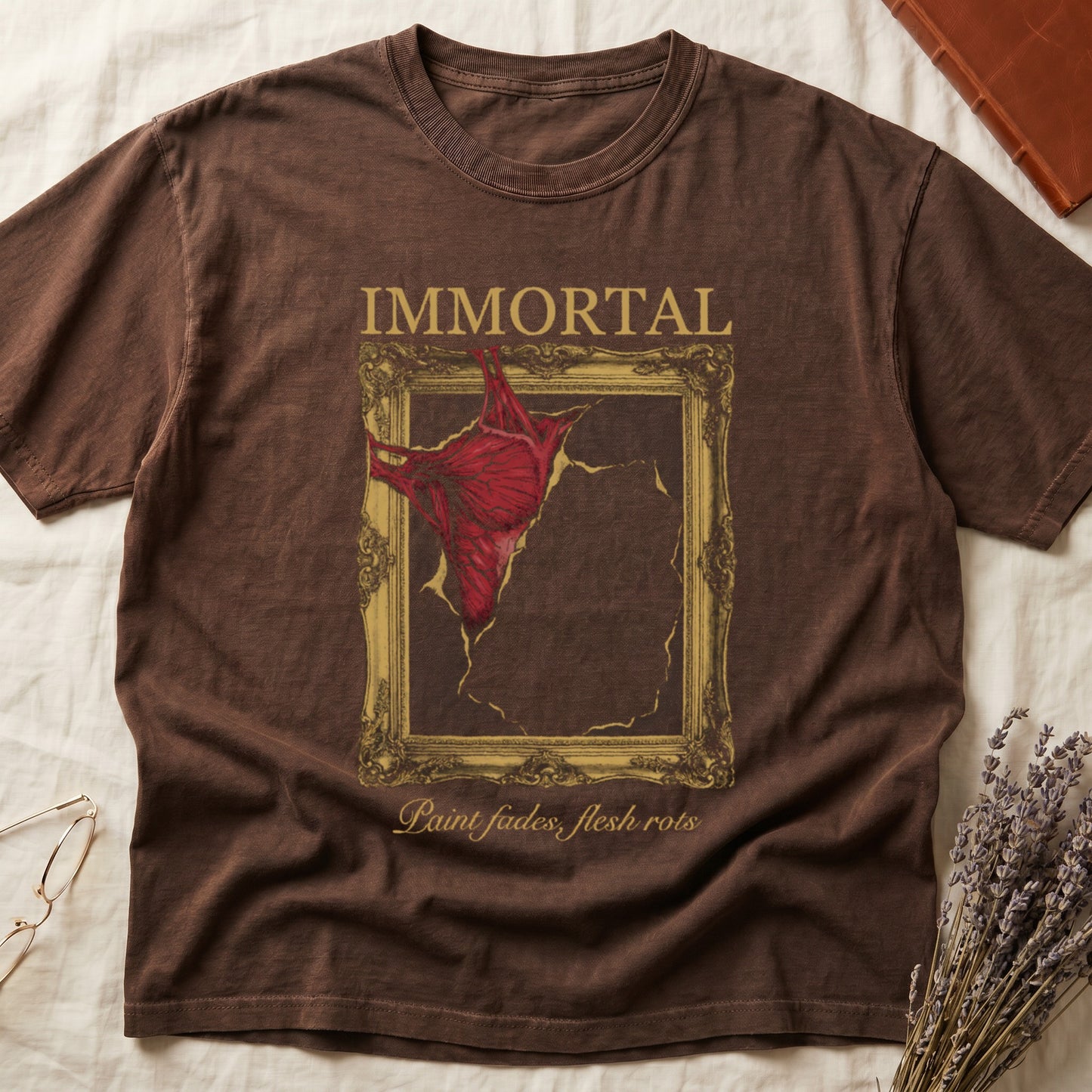 Espresso tee with gold frame and exposed muscle tearing canvas, "IMMORTAL" top, "Paint fades, flesh rots" italic below.