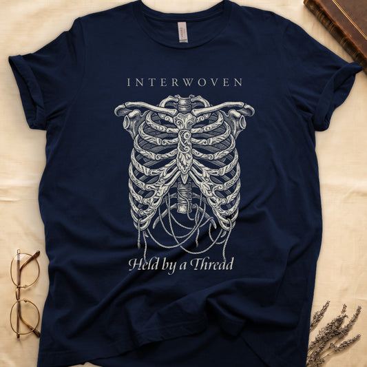 Navy tee with cream skeletal ribcage suspended by trailing threads, "Held by a Thread" in serif on plate below.