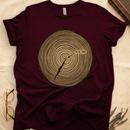 Maroon tee with cross-section of tree rings in warm brown, arrow pointing to center labeled "YEAR ONE" in serif type.