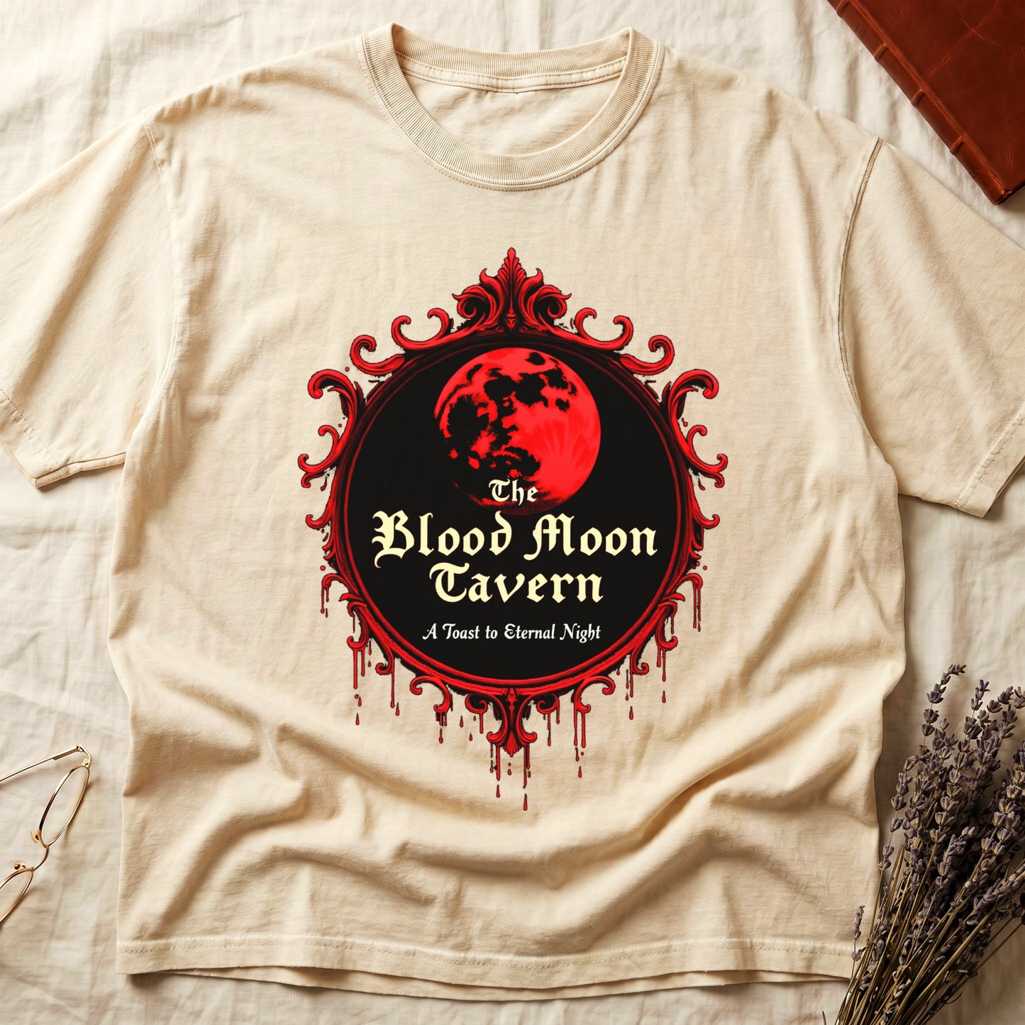 Ivory tee with red oval frame, blood-red moon, "The Blood Moon Tavern," "A Toast to Eternal Night," red drips below.