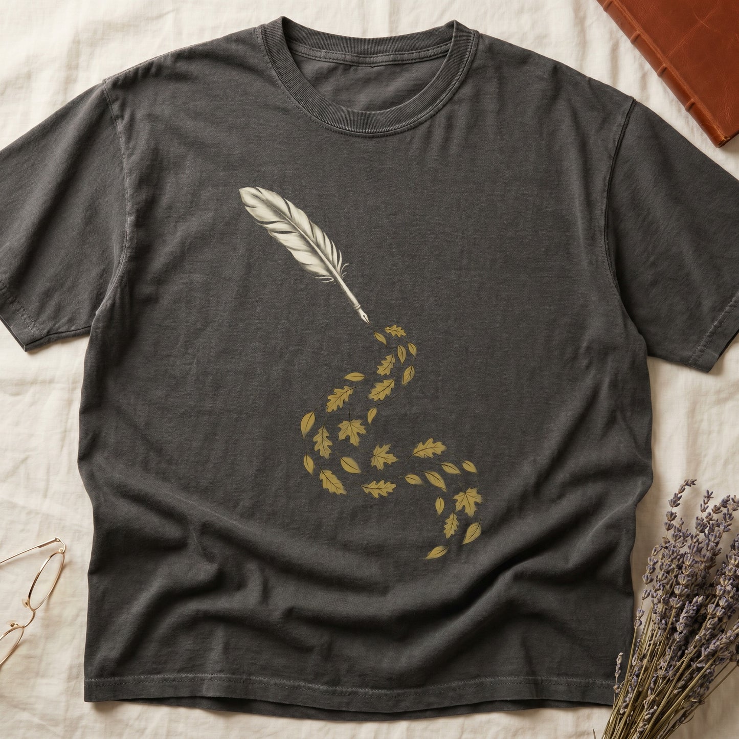 Pepper tee with antique quill pen in cream linework, oak and maple leaves cascading from the nib in gold and green.