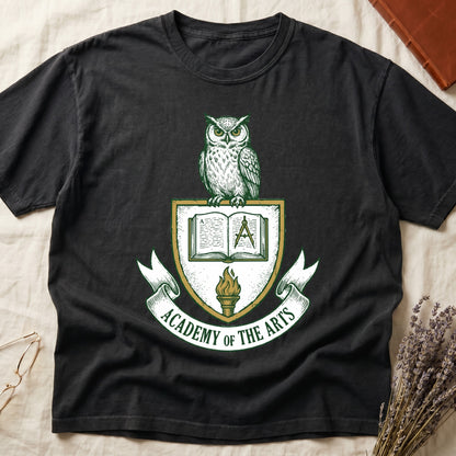 Black tee with heraldic shield crest, owl perched on top, open book and dividers center, "ACADEMY OF THE ARTS" on a banner.