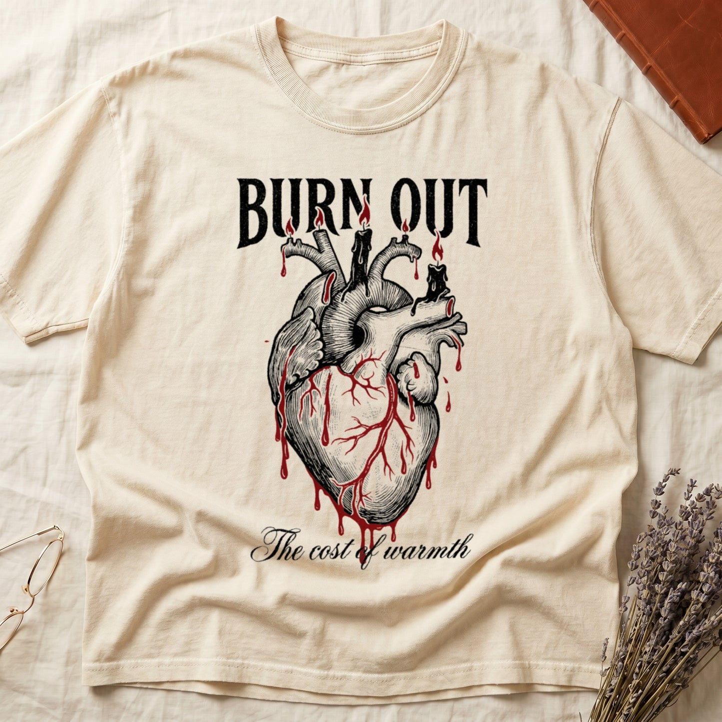 Ivory tee with anatomical heart and melted candles dripping red wax, "BURN OUT" top, "The cost of warmth" cursive below.